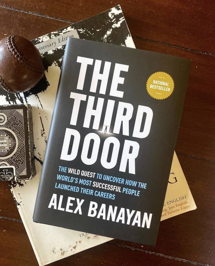 The Third Door book on a table with a deck of cards and a baseball