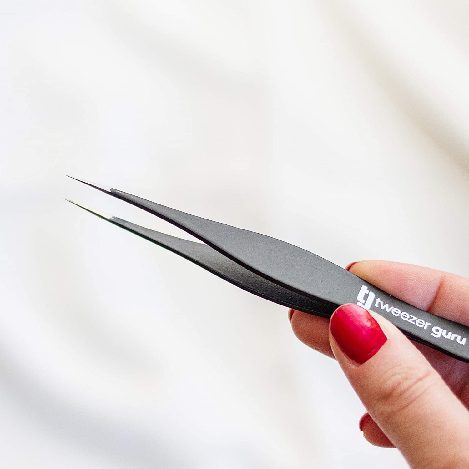 Model's hand holding the tweezers