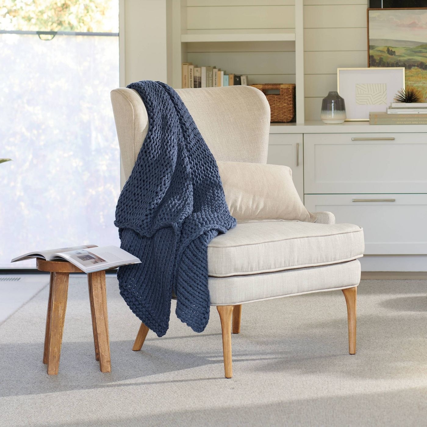 blue chunky knit blanket draped over a white accent chair