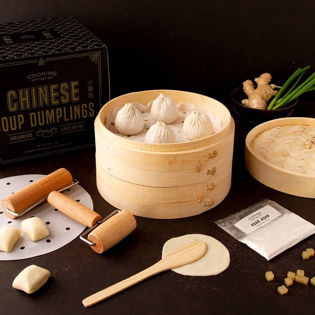 Soup dumplings in wooden basket with tools and dough out around them 