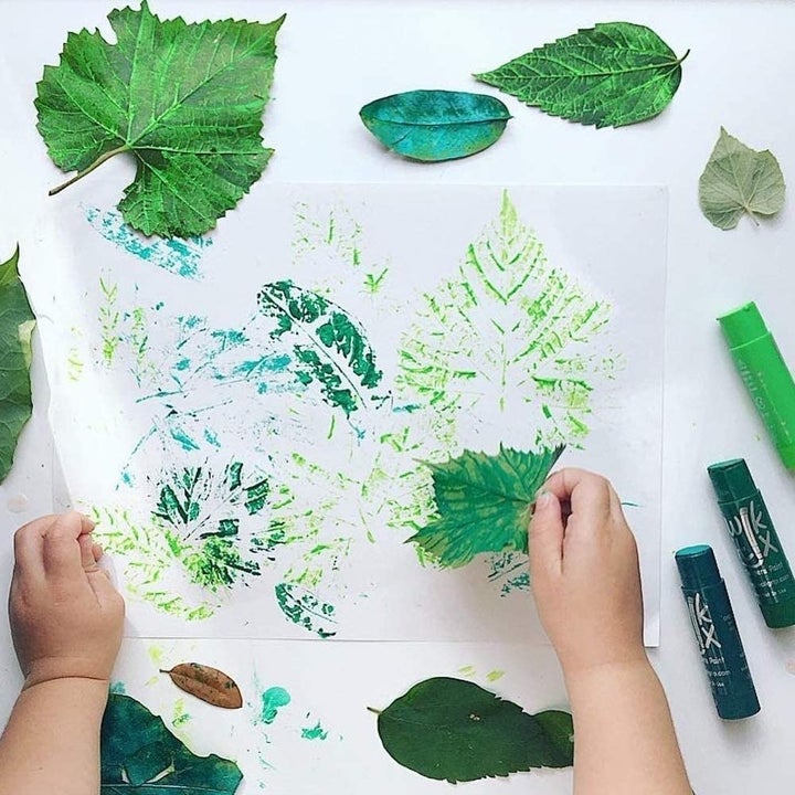 A toddler making art with paint sticks