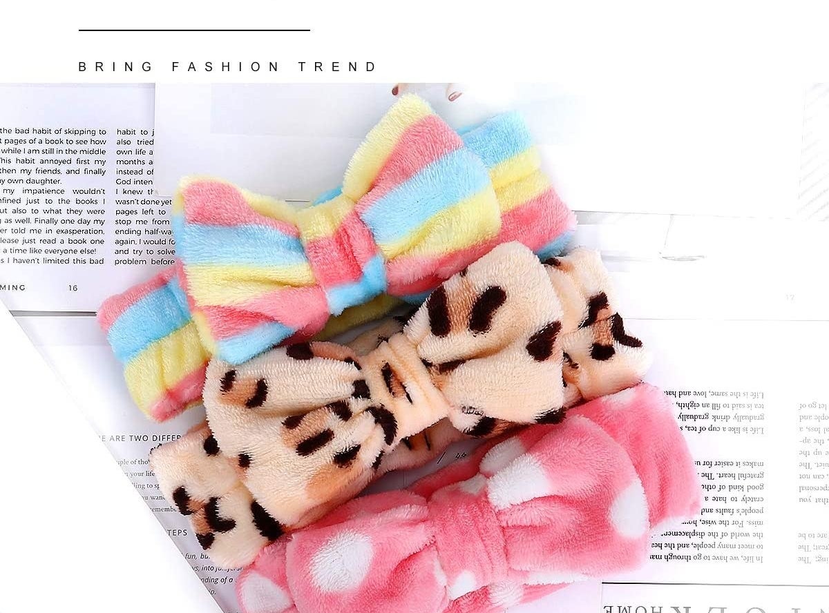 Three fluffy headbands with bows at the front lying on a sheet of paper