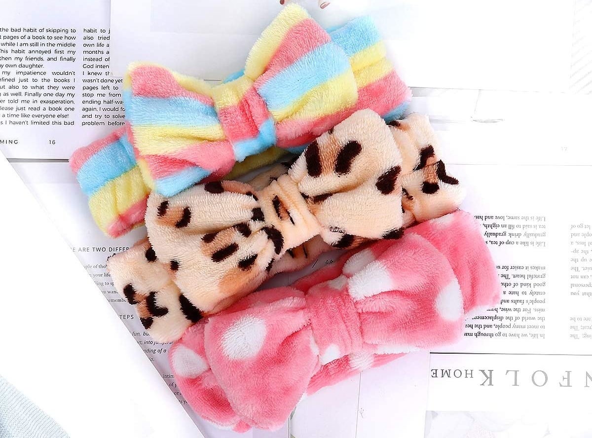 Three fluffy headbands with bows at the front lying on a sheet of paper