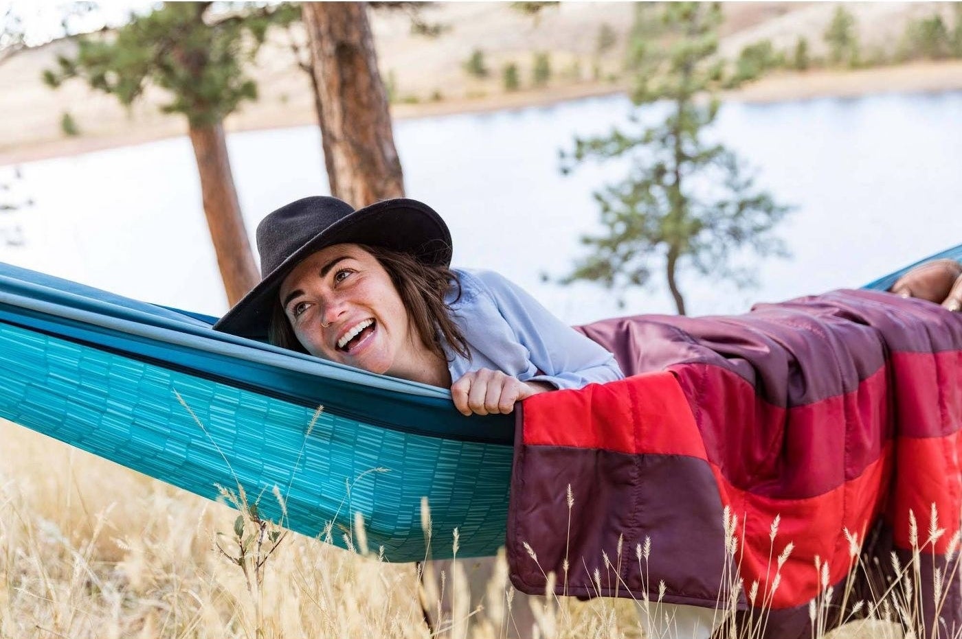 person lounging in a hammock while looking up and smiling