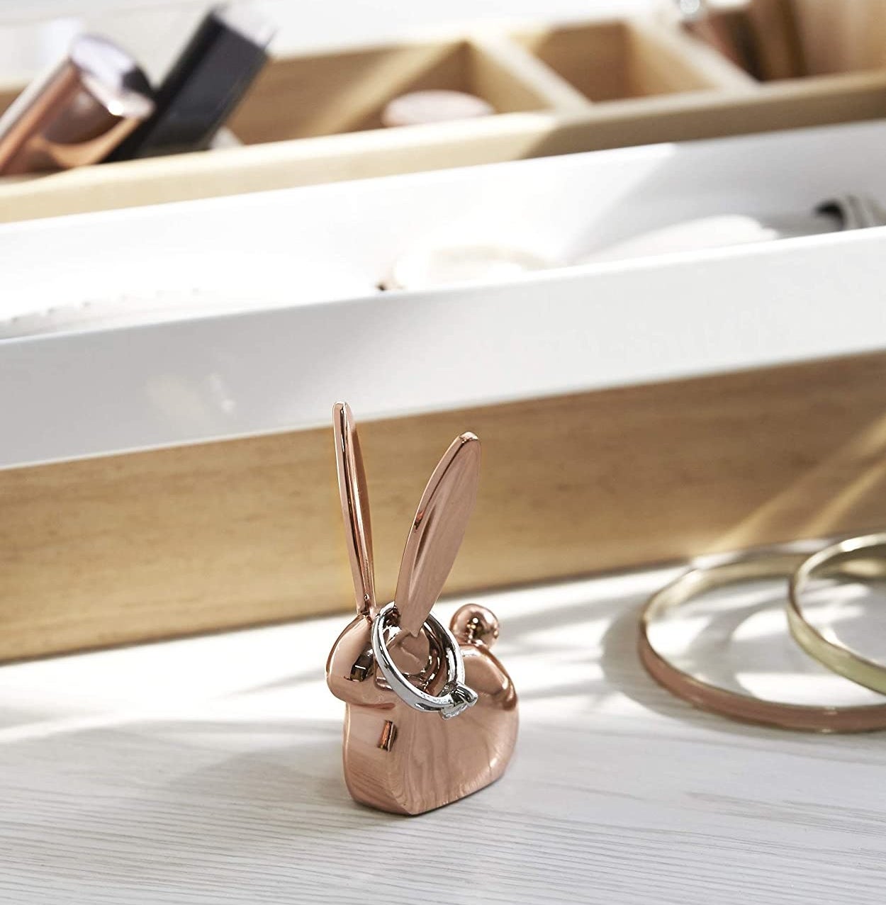 A rabbit-shaped ring holder on a dresser