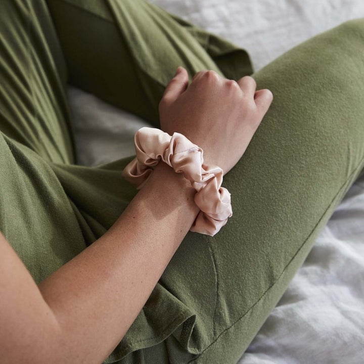A model wearing a silk scrunchie on their wrist