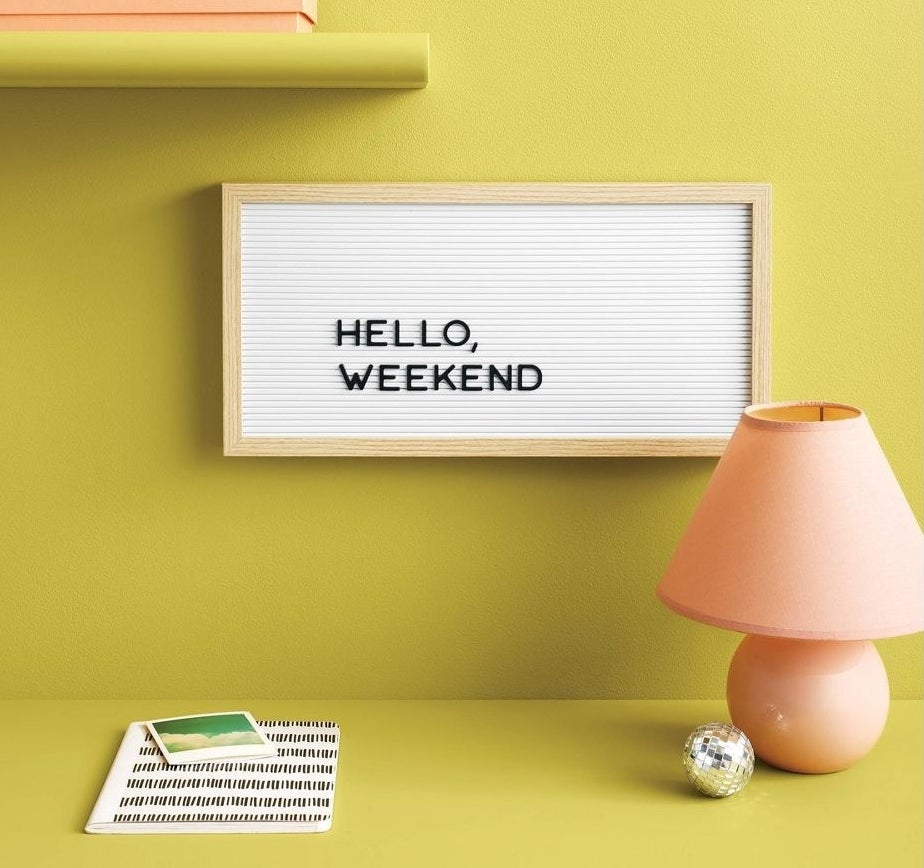 long letterboard with the saying &quot;hello weekend&quot; hung up on a yellow-green wall