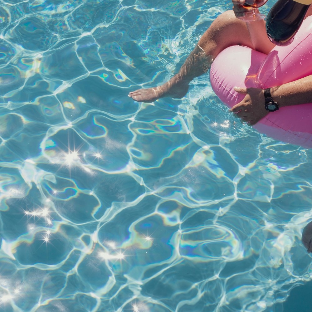 Sun glittering on a pool as someone relaxes on a floatie 