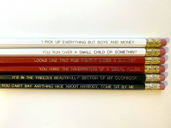 white, red, and black pencils with gold quotes on them