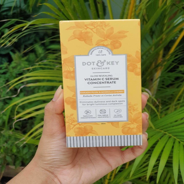 A hand holding the outer box of the serum.