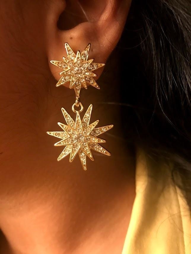A reviewer wearing the earrings, which are two connected stars filled with white crystals