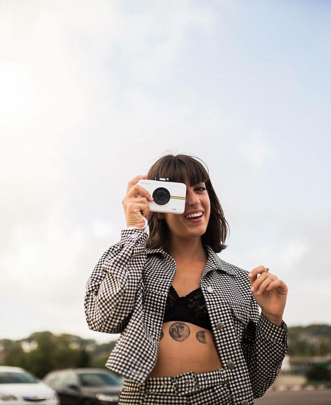 A person holding the Polaroid instant camera in white as if they are taking a picture