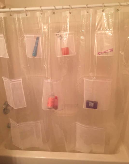 Reviewer pic of the shower curtain with several different products in the attached pockets 