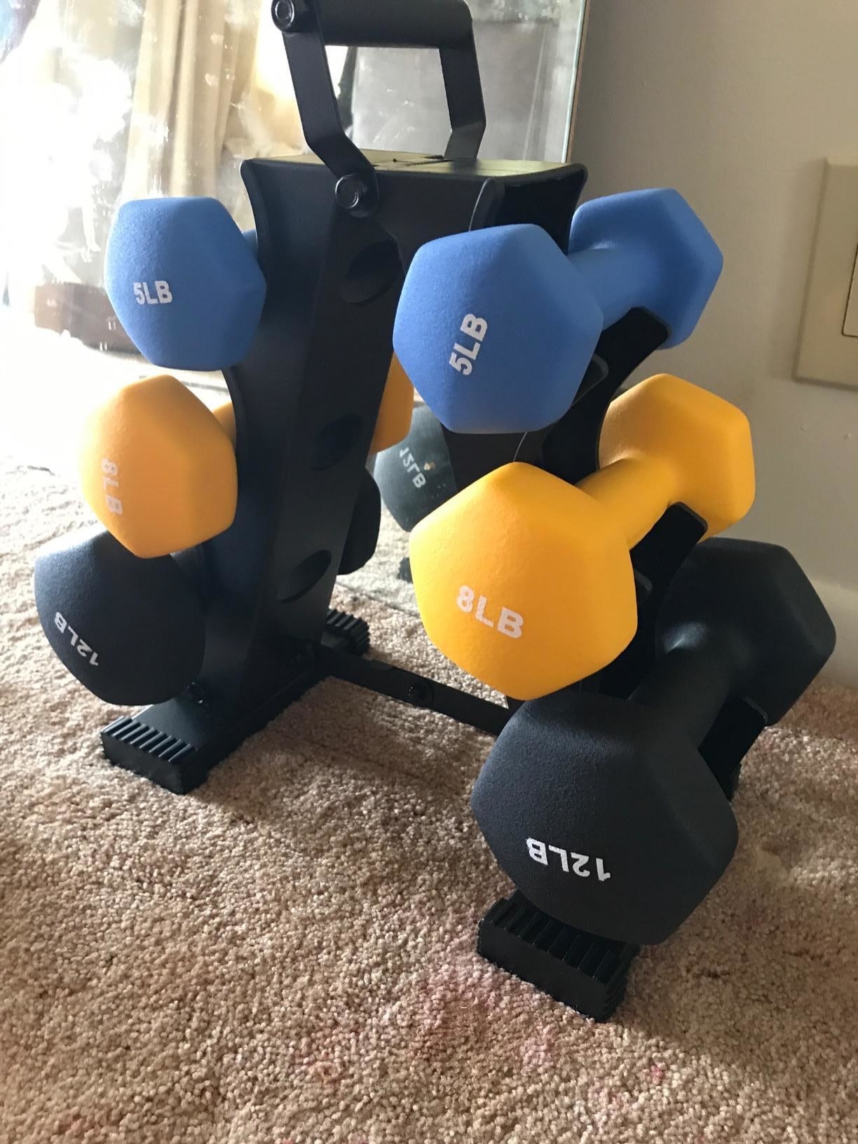 Reviewer pic of the five, eight, and 12-pound dumbells on a black stand