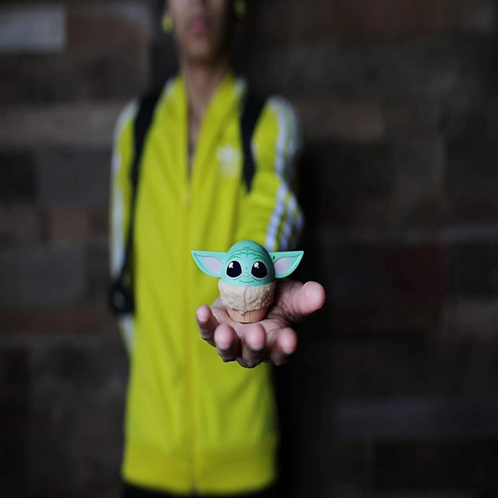 A model holding the round speaker with ears in the palm of their hand