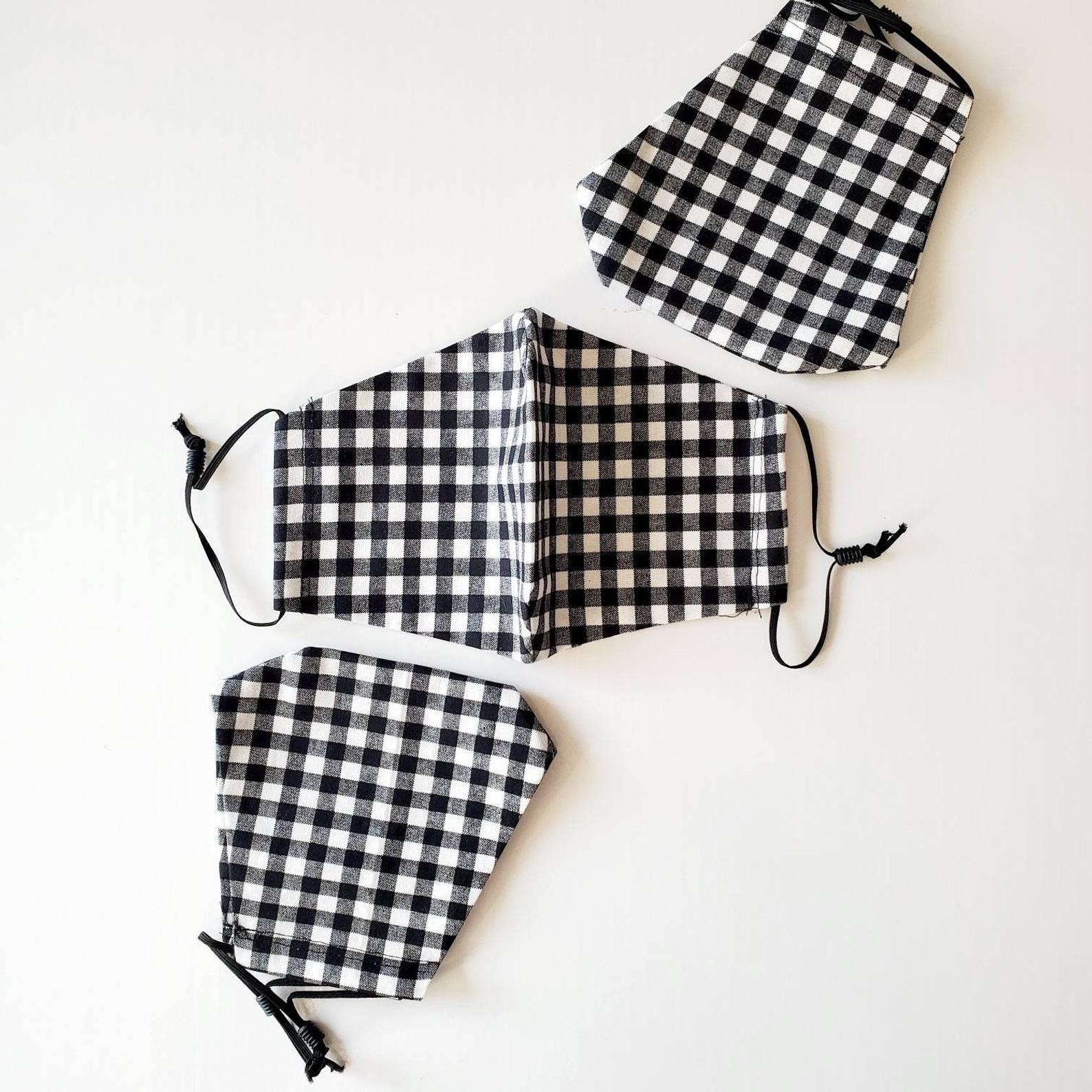 An abstract white and black face mask and two gray face masks