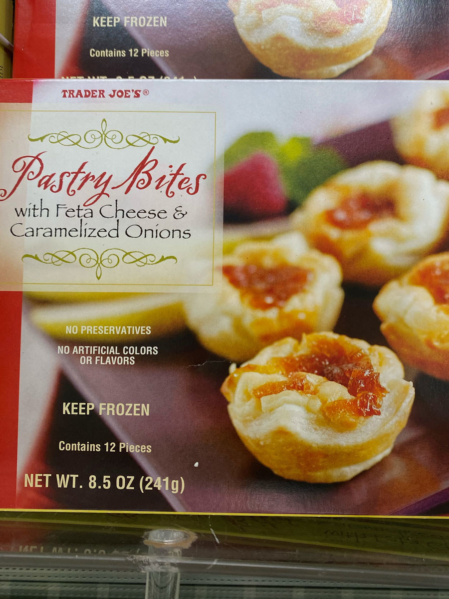 A box of pastry bites with feta and caramelized onions.