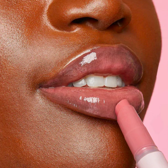A close up of a person smoothing the lip gloss onto their lips