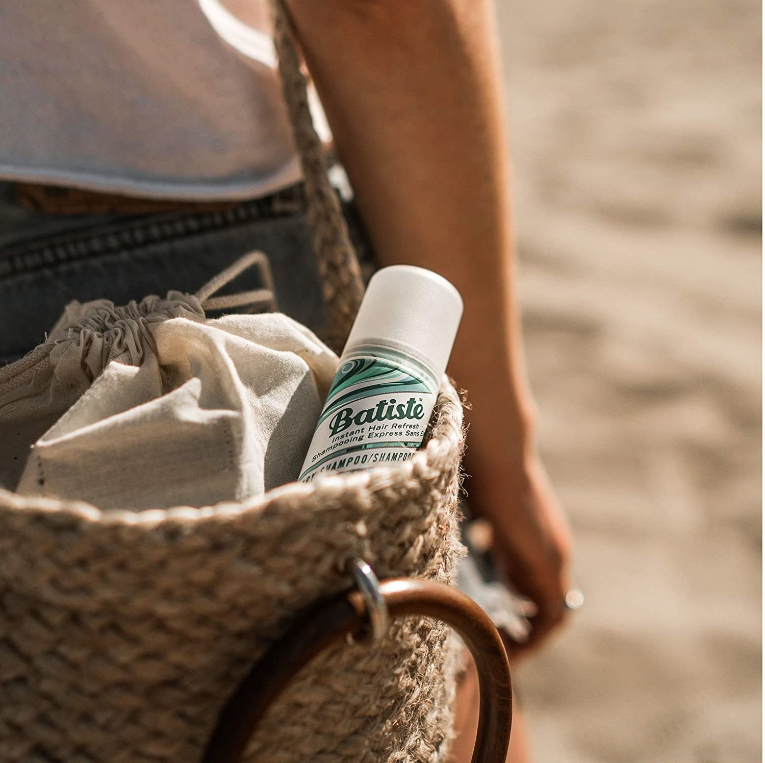 A bottle of Batiste dry shampoo poking out of a model's purse