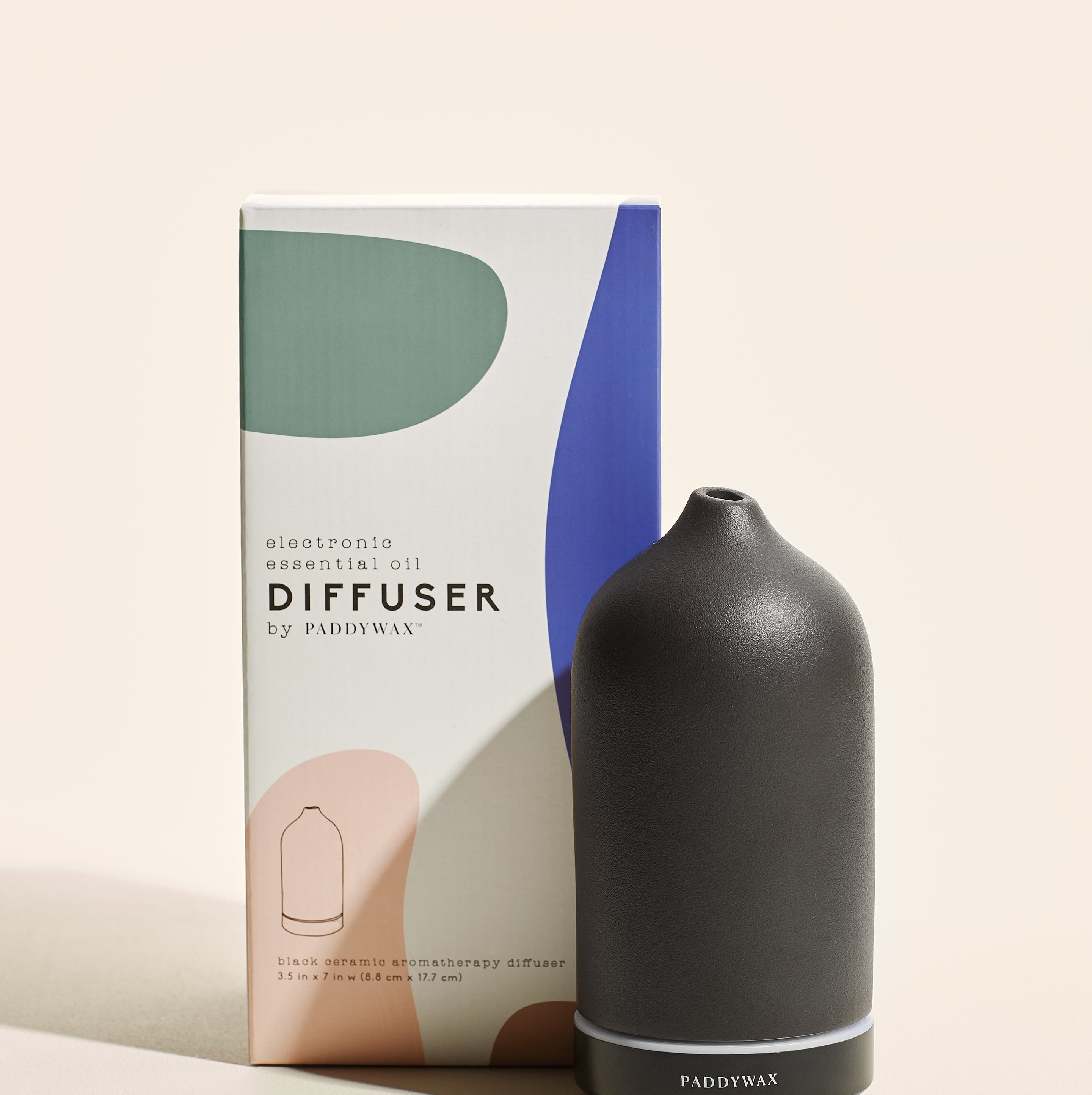 The black essential oil diffuser posed in front of its packaging
