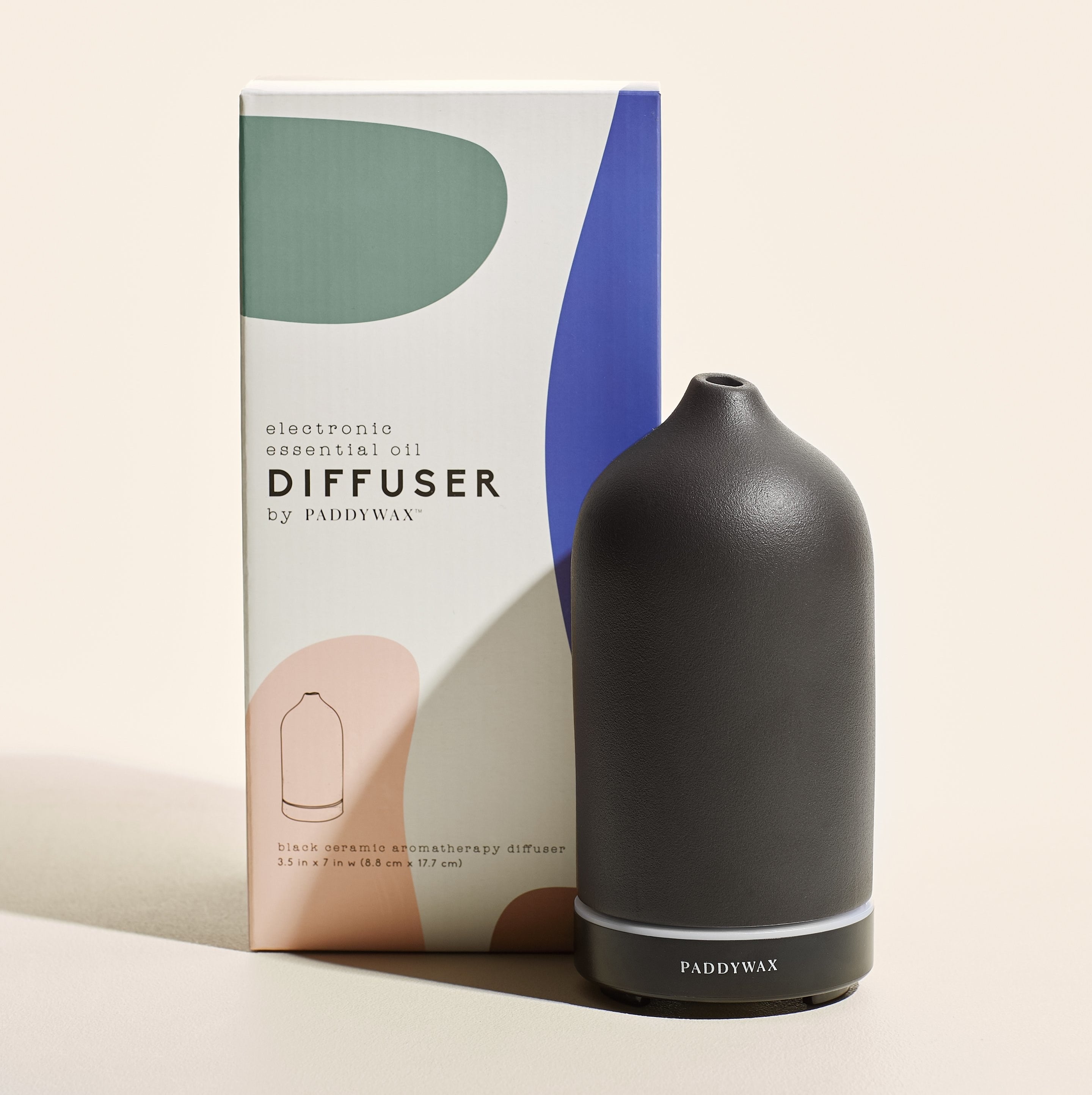 The black essential oil diffuser posed in front of its packaging