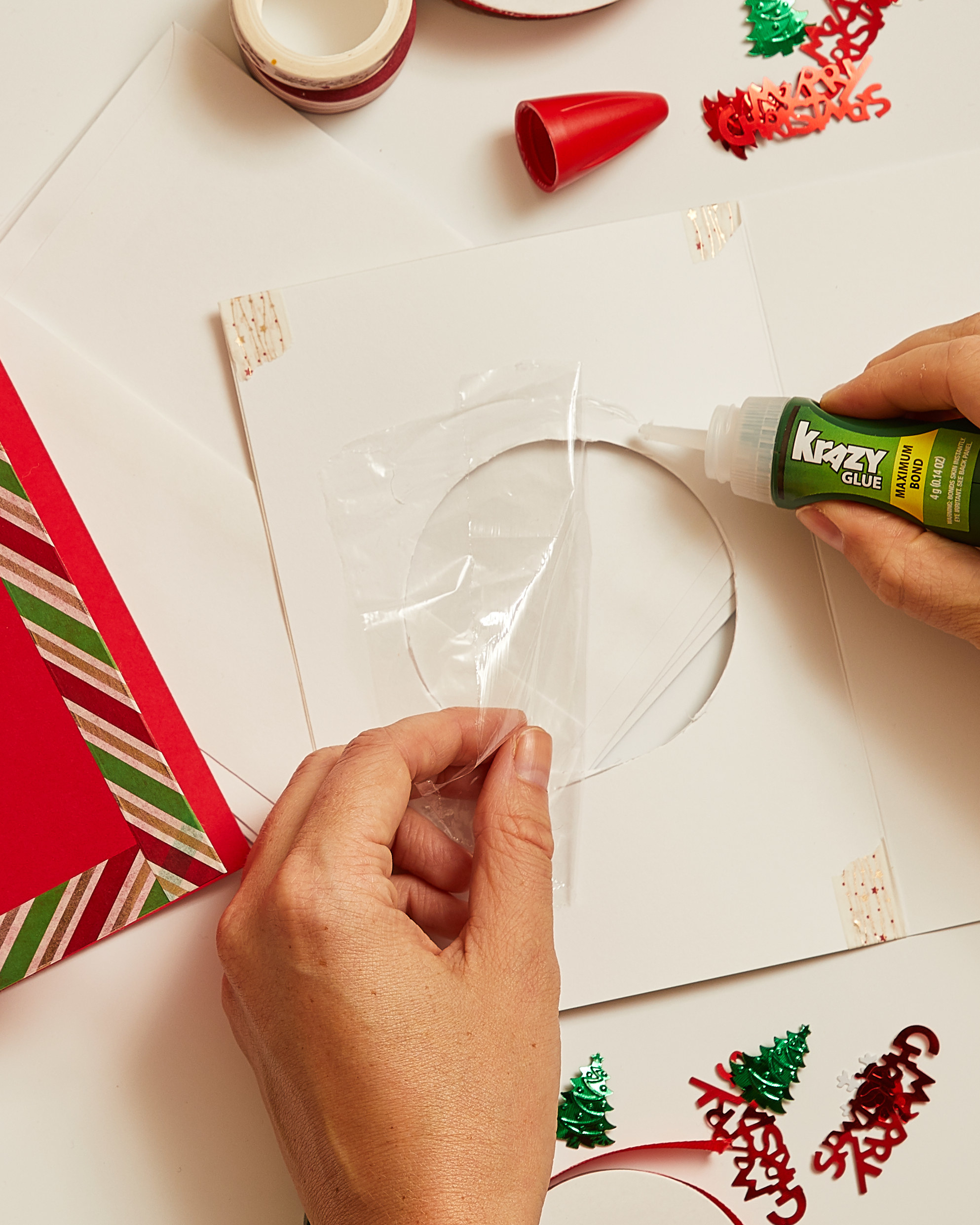 Person Krazy Gluing cellophane to the inside of an open card with a circular cutout.