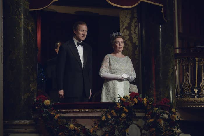 Tobias Menzies as Prince Philip and Olivia Coleman as Queen Elizabeth II standing in a theater balcony