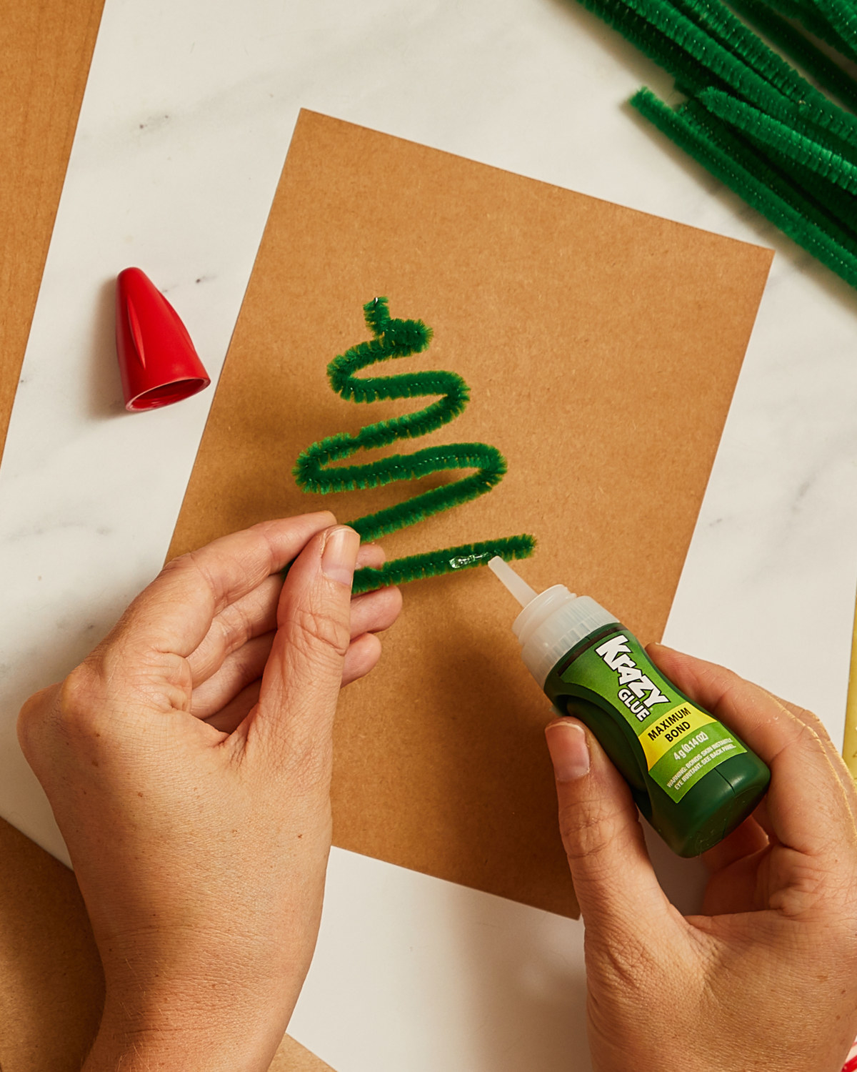 Person Krazy Gluing shaped pipe cleaner to card.