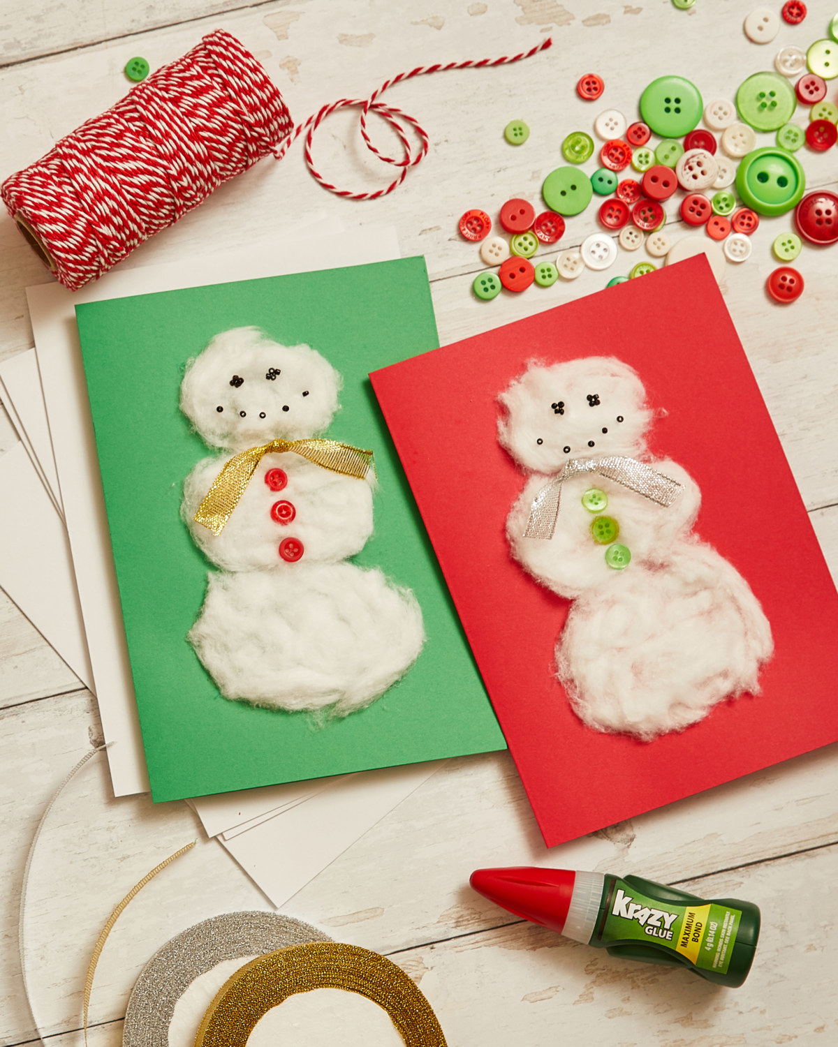 Completed cotton ball snowman card. Ribbon, buttons, and Krazy Glue arranged nicely on wooden table.