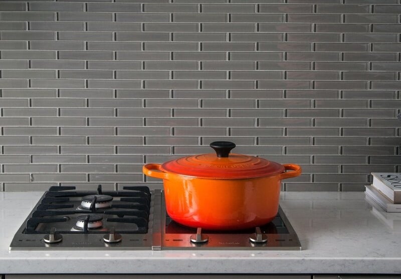 An orange Le Creuset dutch oven in orange on a stovetop