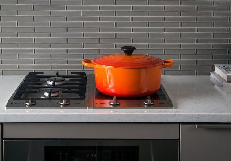 An orange Le Creuset dutch oven in orange on a stovetop