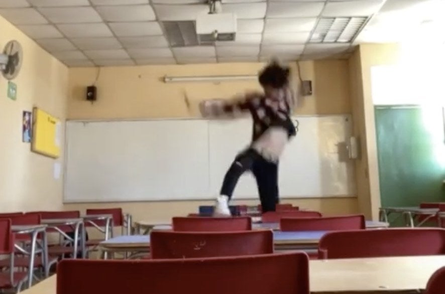 A man appears to fall off of a classroom desk