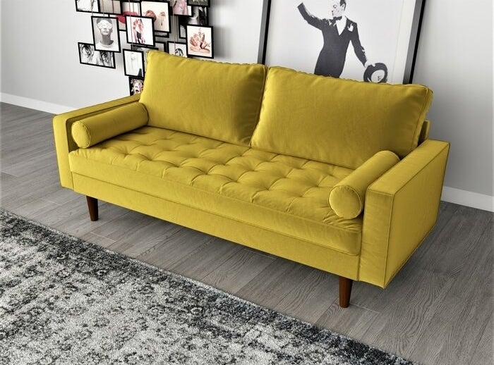 a yellow velvet couch sitting in a living room