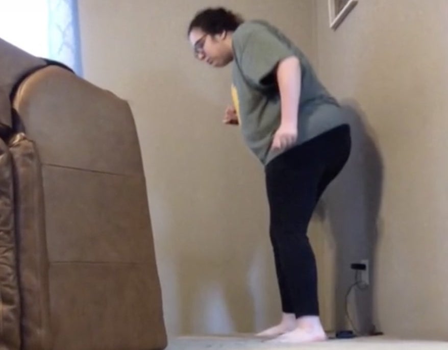 A woman looks under her living room chair for something
