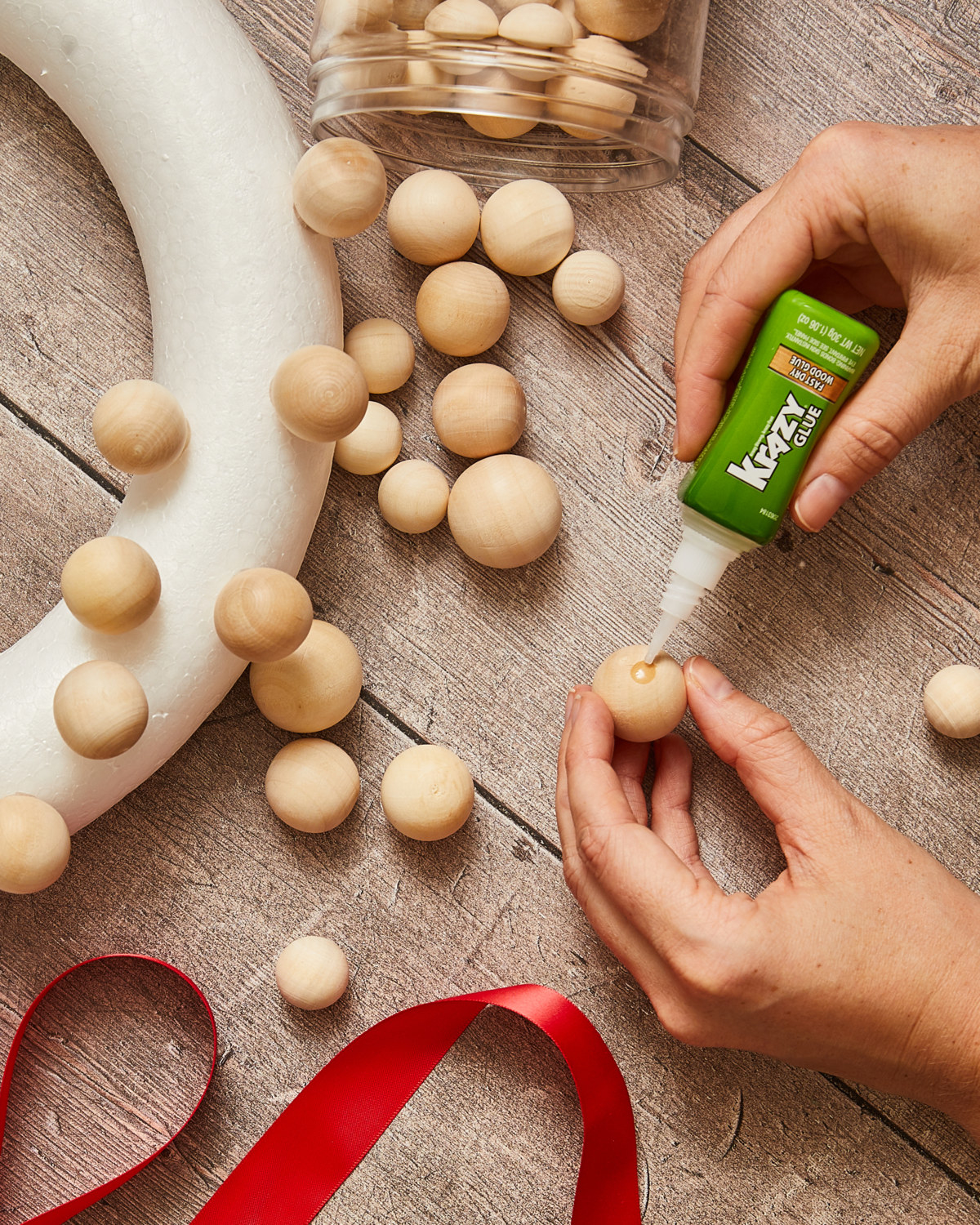 Person Krazy Gluing unpainted wooden balls to wreath form.