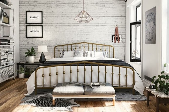gold platform bed in a bedroom with white linens on top