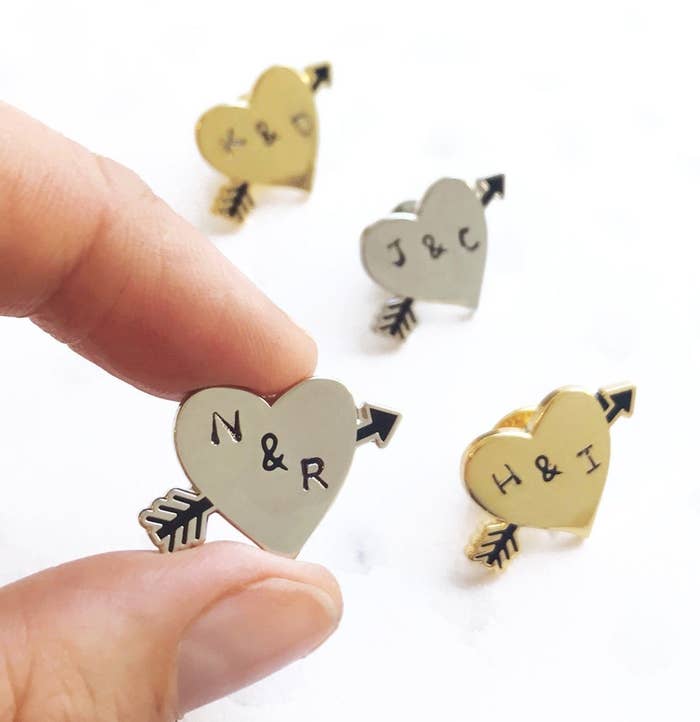 heart pins with an arrow through it and two letter initials 