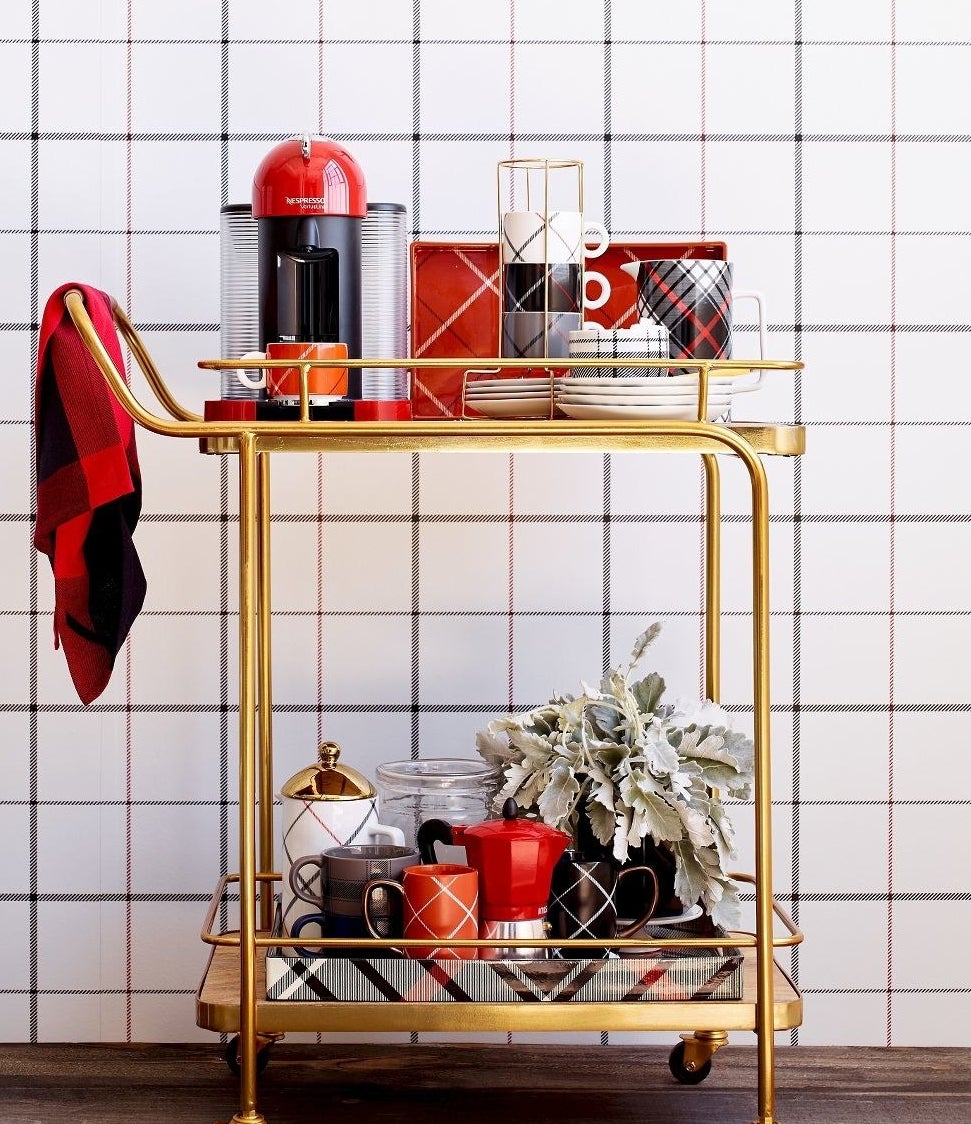 Bar cart with gold frame, wooden shelves, and leather handles