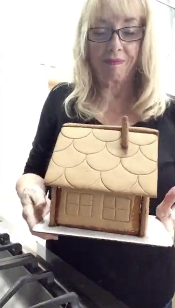 Anita holding her undecorated gingerbread house