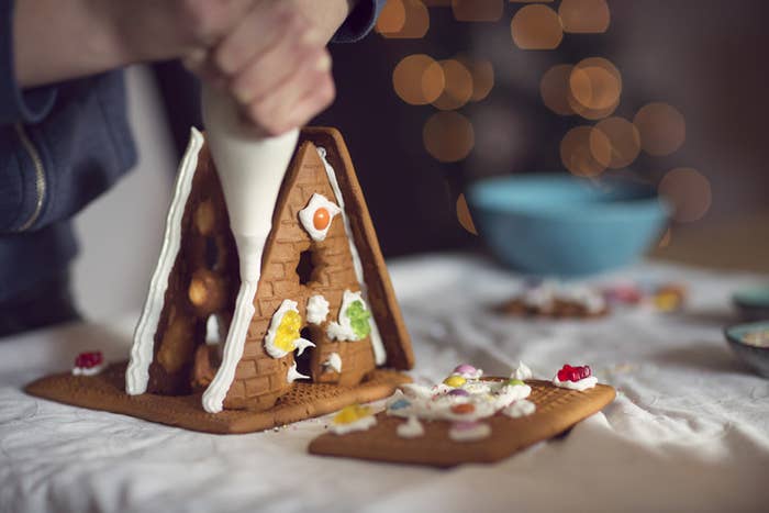A person trying to put together a small gingerbread house
