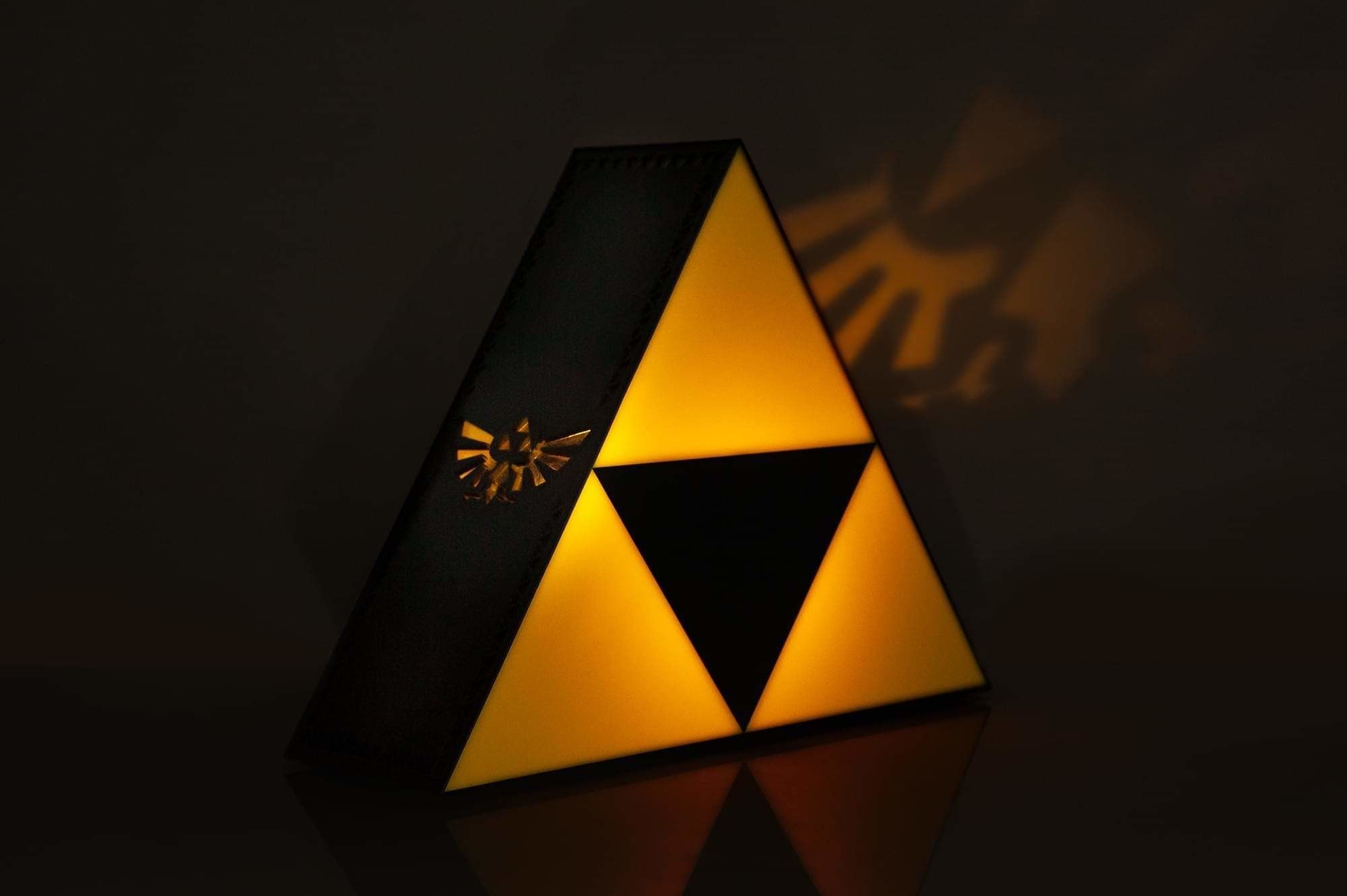 The triangular light lit up yellow and projecting the Triforce symbol on a wall from the side