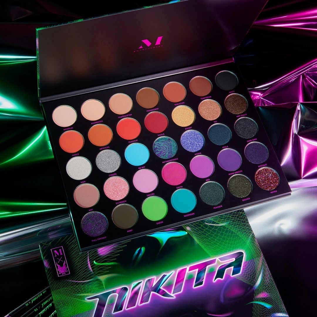 An open palette showing all the shades of the eyeshadows against a neon-noir backdrop