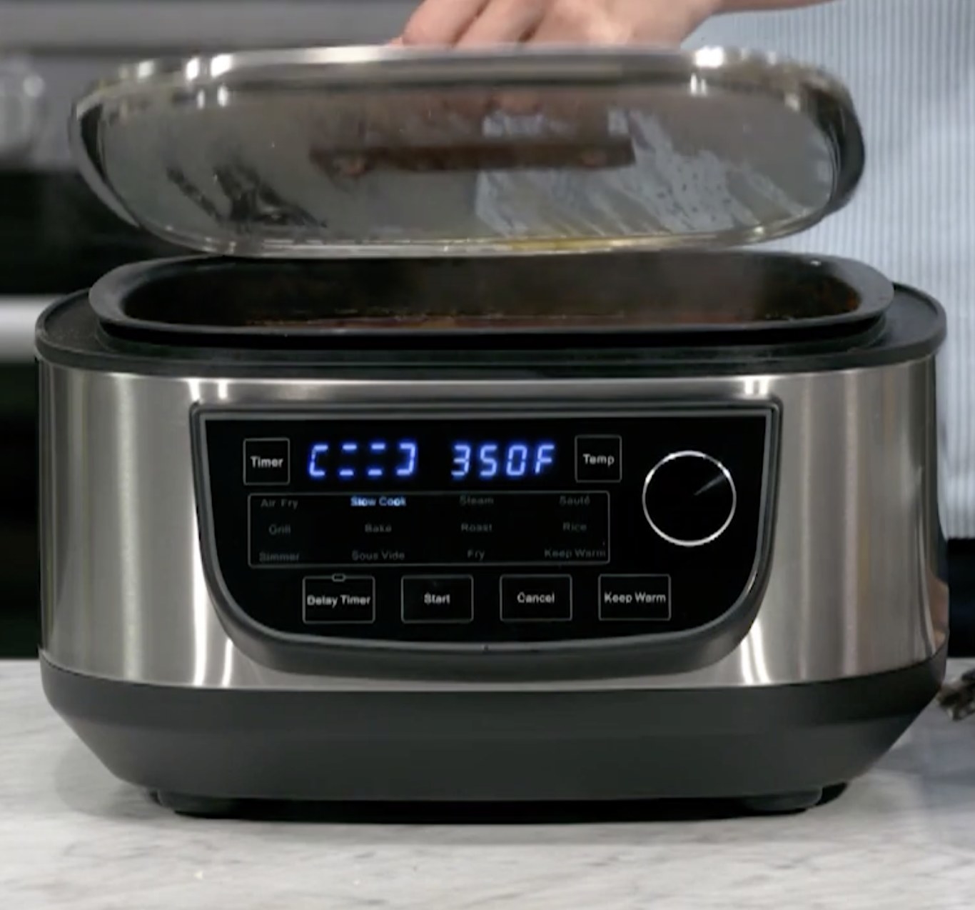 Person is holding the lid to the grill and air fryer