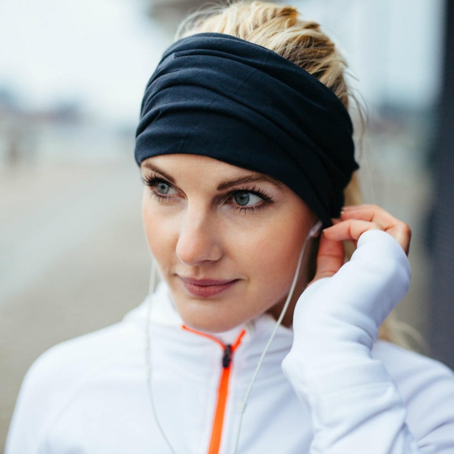 woman with headband on putting an earphone in her ear