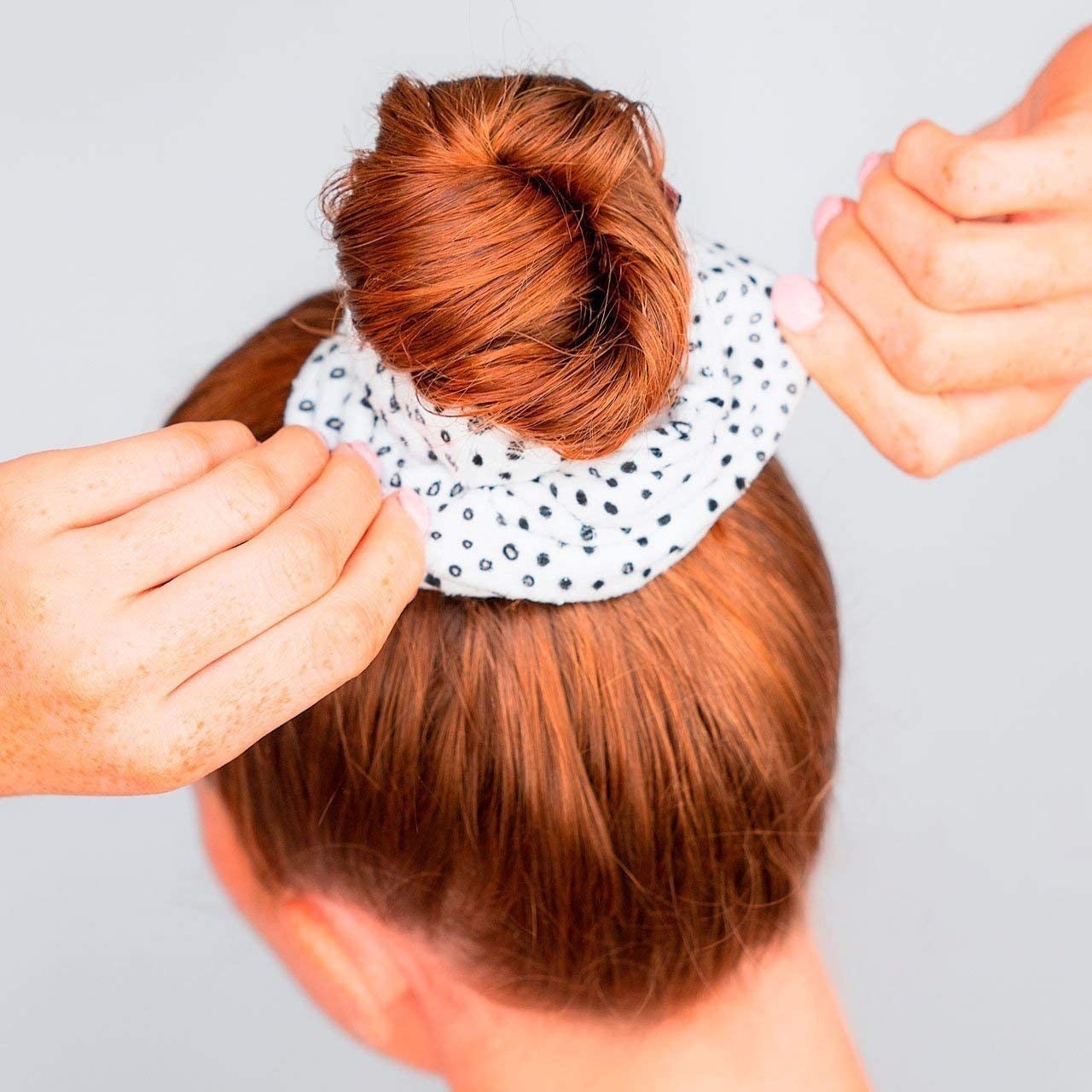 A rear view of a person wearing their hair in a bun, secured by the terrycloth scrunchie