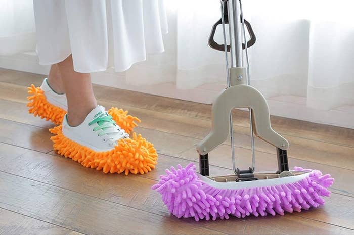 A person wearing microfibre slippers over their shoes to clean their floor