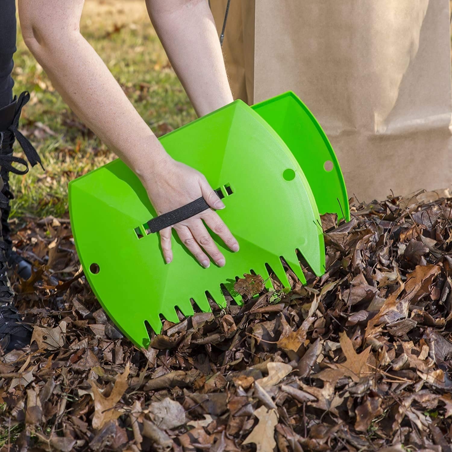 A person picking up a pile of leaves with huge claw-like leaf scoops on their hands