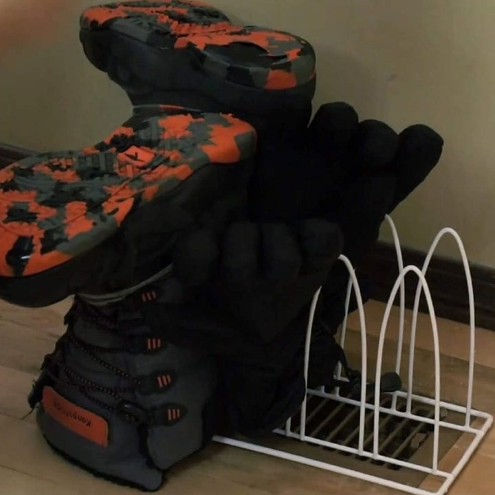 The rack over a floor vent with a pair of boots and mittens on it