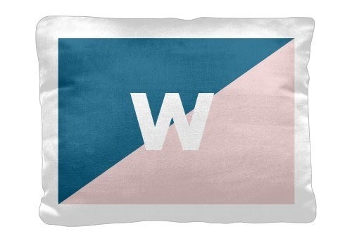 a white pillow with a blue and white diagonal design of blue and pink and a W in the middle