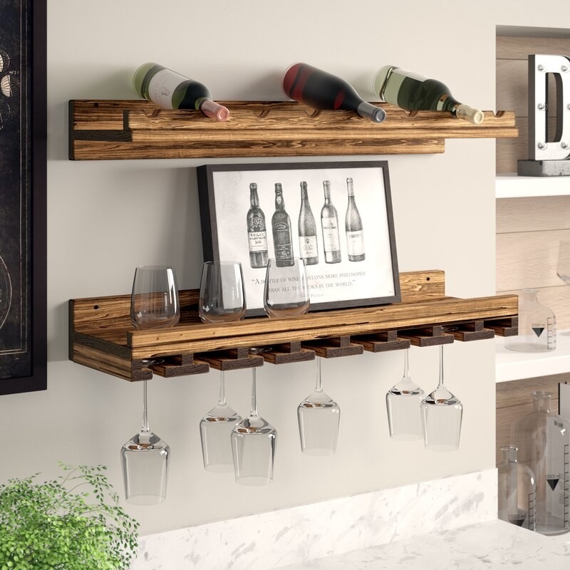 One wooden shelf with divets for wine bottles and another with slots for wine glasses